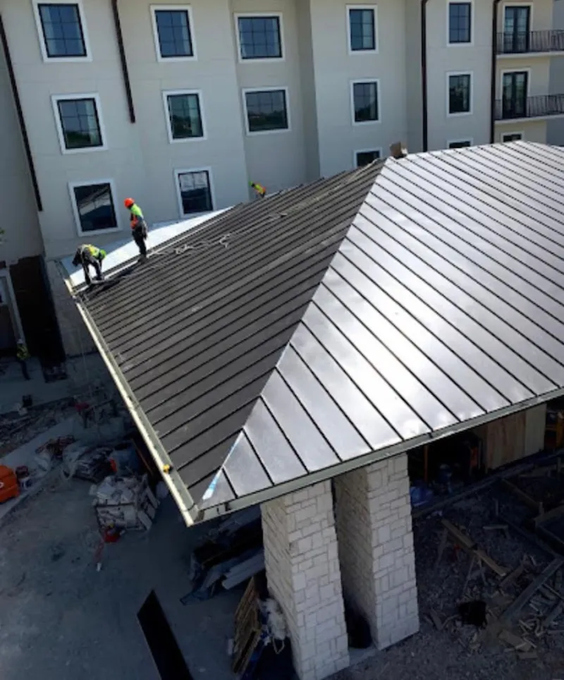Crew installing standing seam metal roof panels on a commercial project in Grants